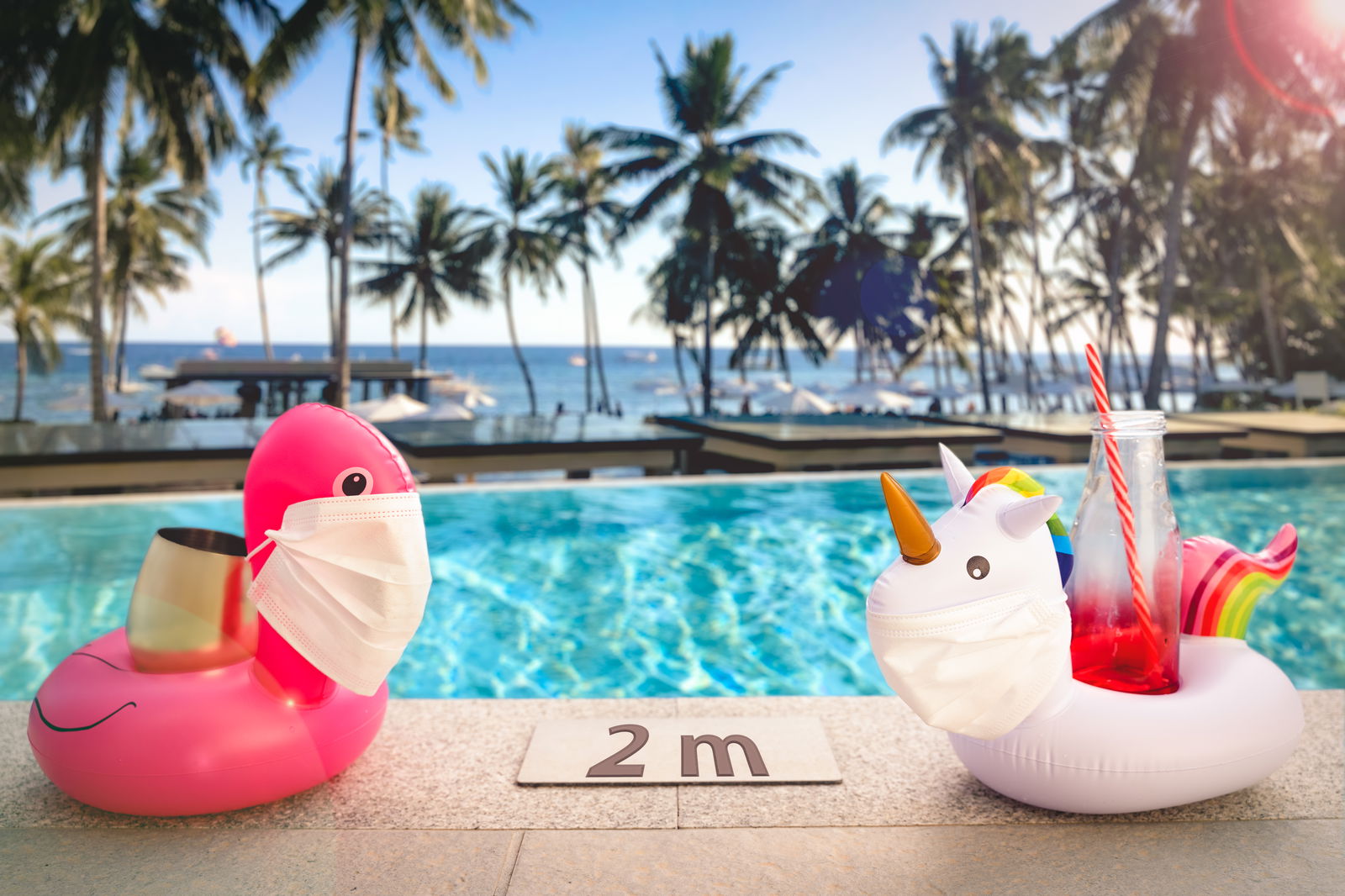 ein aufblasbarer Flamingo und ein aufblasbares Einhorn mit Mund-Nasen-Schutz am Pool