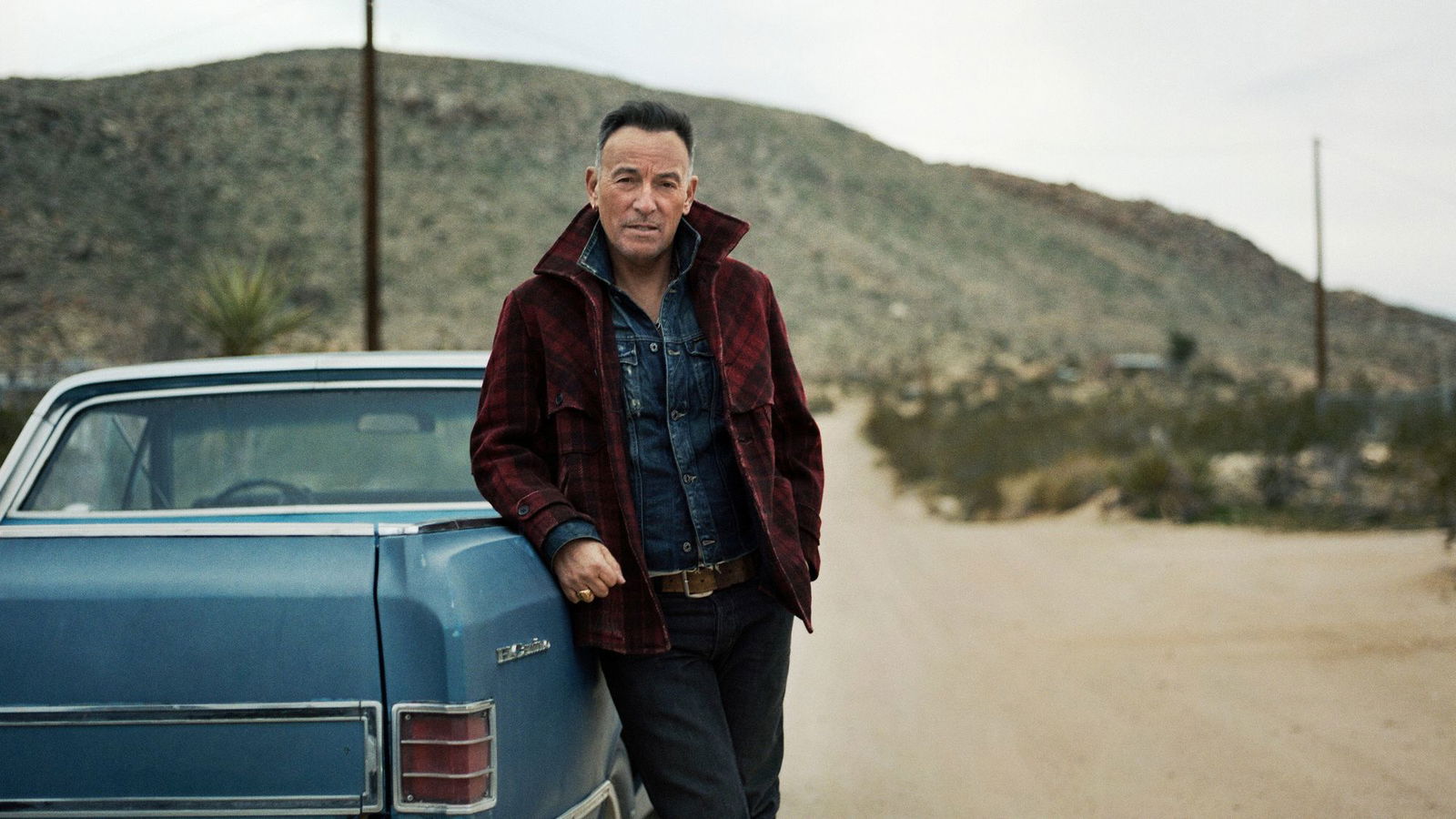 Bruce Springsteen lehnt an einem hellblauen Pickup-Truck